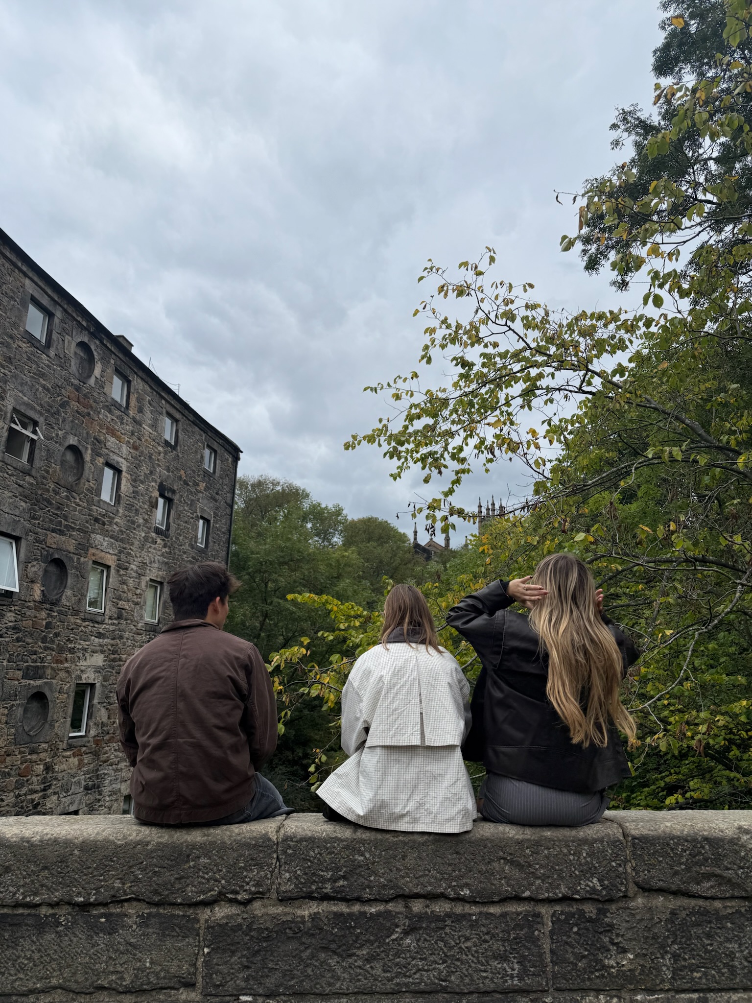 Three friends on a stone wall in Edinburgh